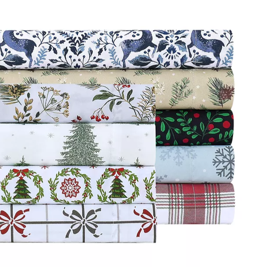 A stack of holiday-themed fabric sheets featuring various patterns, including reindeer, pine branches, Christmas trees, holly, snowflakes, and plaid design.