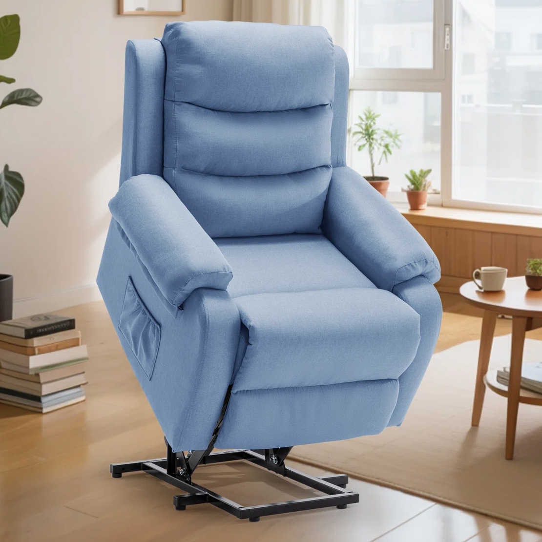 A light blue lift chair recliner with padded armrests and a side pocket is shown in a cozy living room setting with wooden floors and plants.