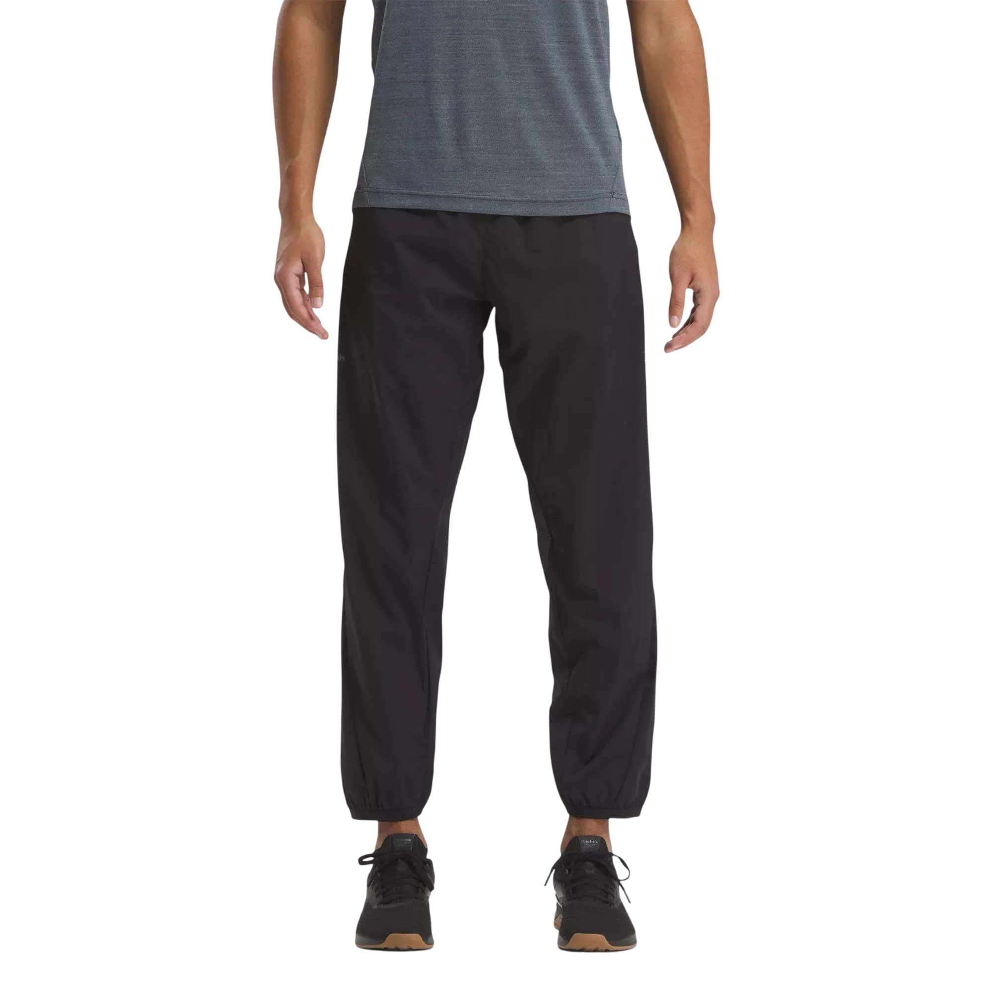 Man wearing black jogger pants with elastic cuffs, paired with a blue shirt and black sneakers.