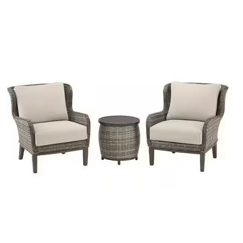 The Cooper Lake Wicker Conversation Set includes two gray wicker armchairs with beige cushions and a matching round side table. The design is simple and elegant, suitable for outdoor settings.