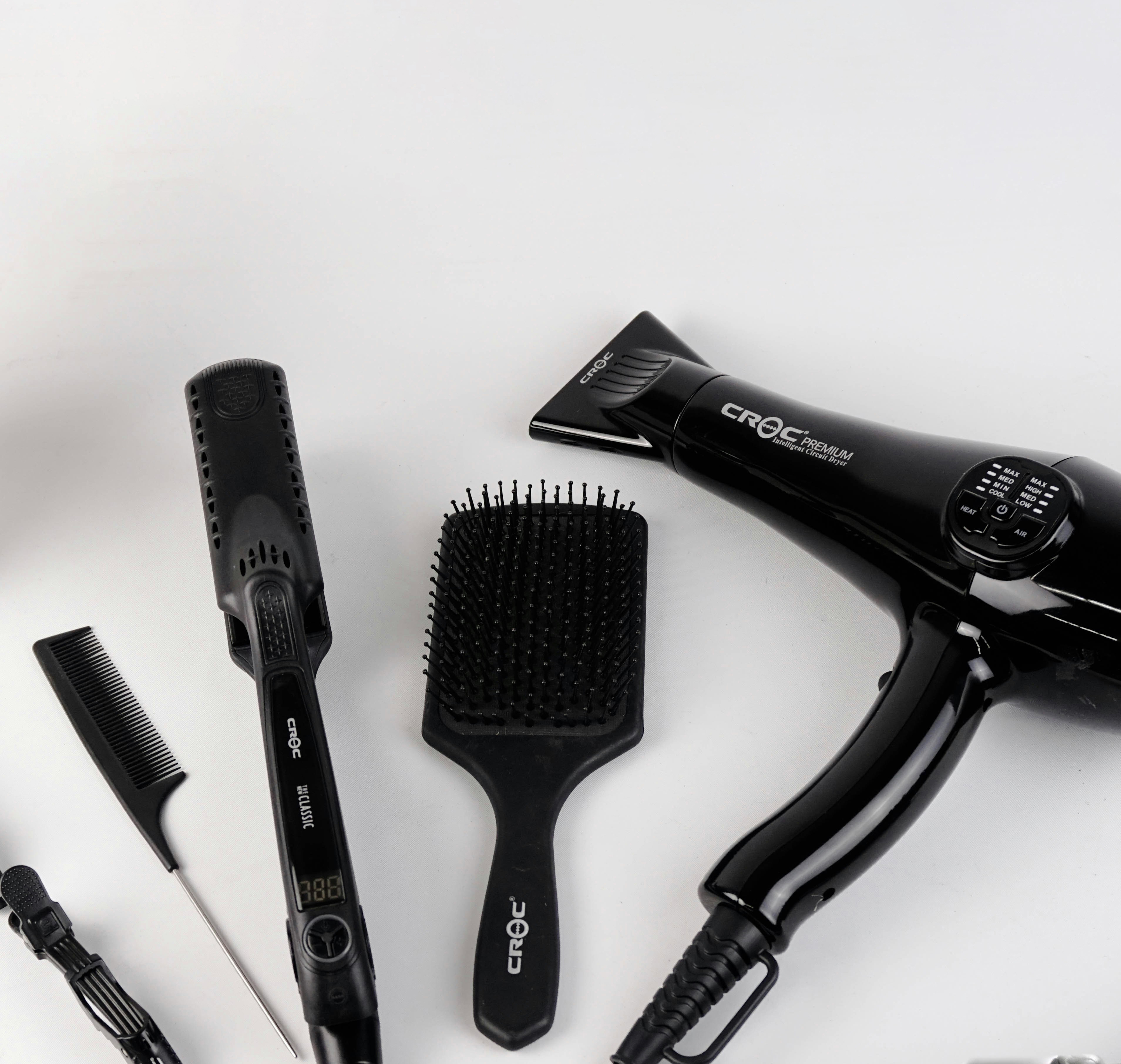 A variety of hair styling tools including a hairdryer, straightener, curling wand, and brushes.