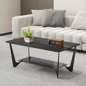 A modern living room setup featuring a black marble coffee table with a minimalist design, displaying a small potted plant and a digital clock. A light-colored sectional sofa with gray and beige cushions is in the background.