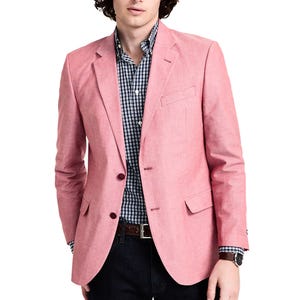 A man is wearing a pink blazer over a black and white checkered shirt, paired with dark jeans.