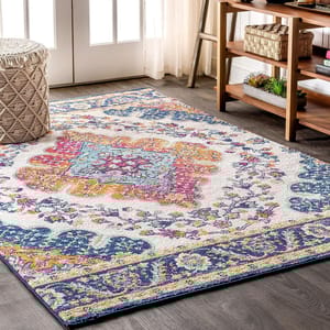 A colorful area rug with a traditional floral pattern is laid out on a wooden floor in a room with furniture.