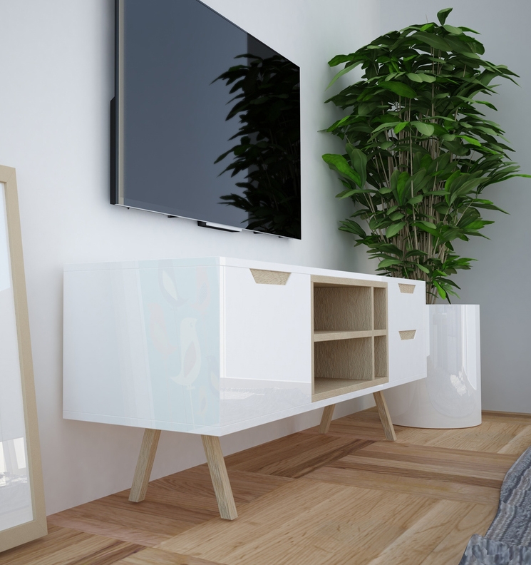 A white modern TV cabinet with decorative patterns and angled wooden legs, next to a green potted plant and underneath a wall-mounted flat-screen TV.