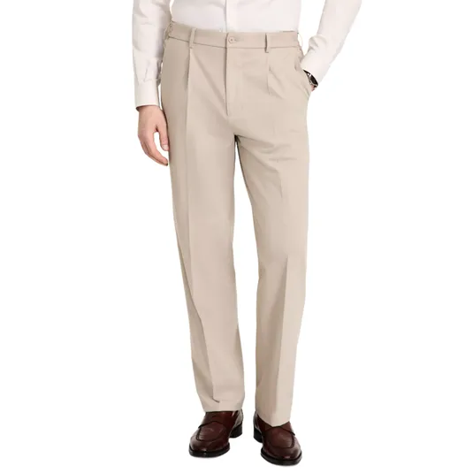 A man is wearing beige dress pants with a pleated front, paired with a white shirt and brown leather loafers.