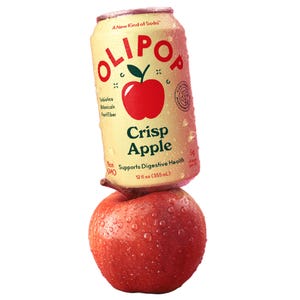 A can of OLIPOP Crisp Apple soda, described as a new kind of soda supporting digestive health, is balanced on a dewy red apple. The can contains 12 fl oz (355 mL) and is non-GMO with 5g of sugar per can.