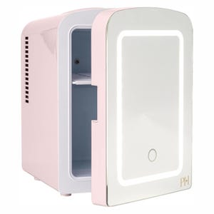 A compact, pastel pink fridge with a mirrored door featuring an integrated LED light and a small touch button. The initials \“PH\“ are displayed on the lower corner.