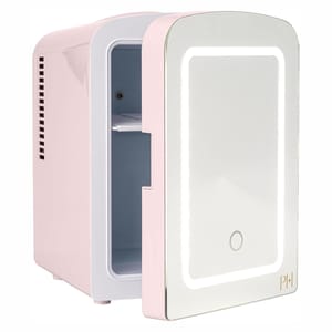A compact, pastel pink fridge with a mirrored door featuring an integrated LED light and a small touch button. The initials \“PH\“ are displayed on the lower corner.