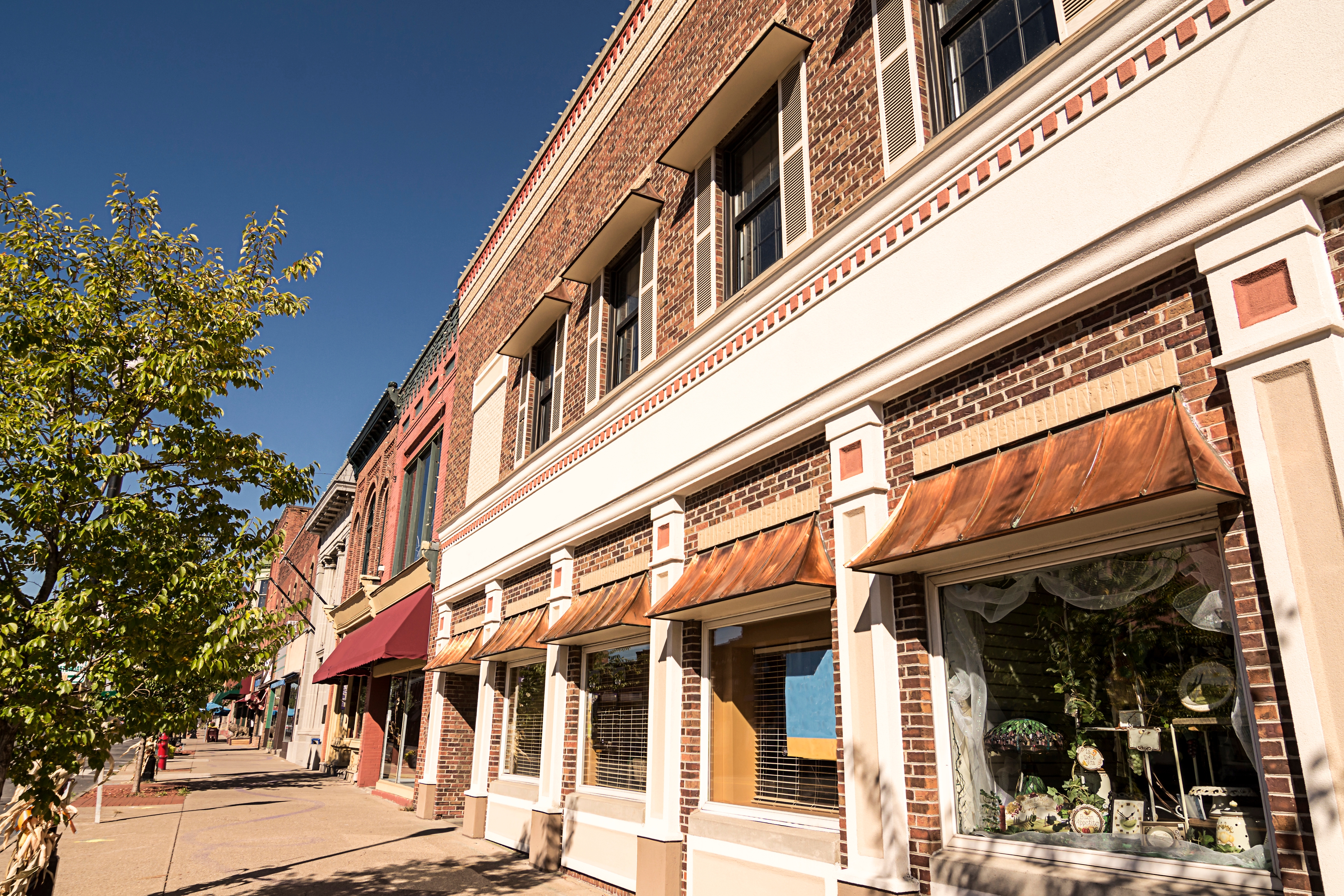 A street lined with traditional brick buildings and retail storefronts under awnings.