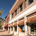 A street lined with traditional brick buildings and retail storefronts under awnings.