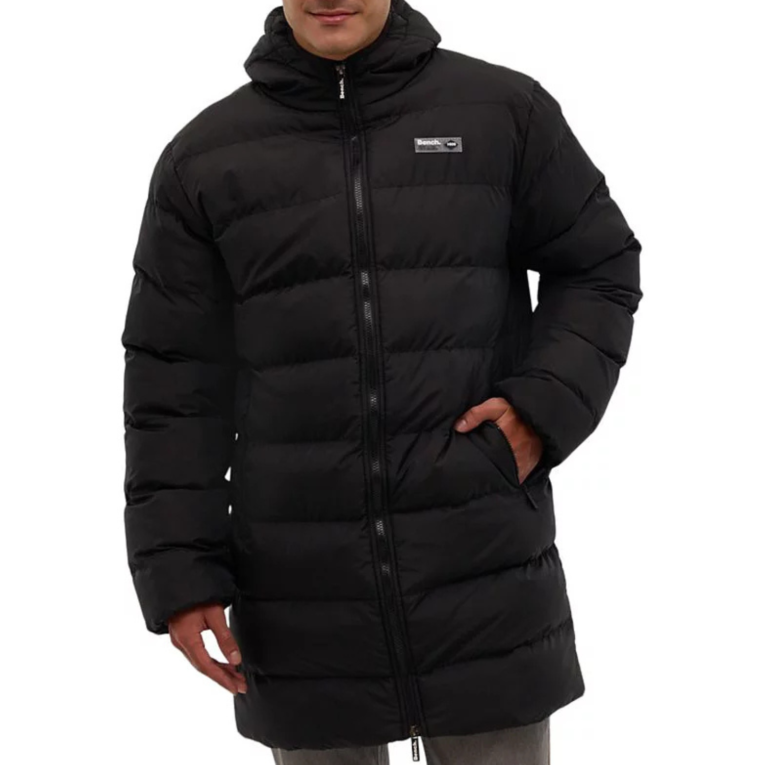 The Bench DNA Puffer Coat is a black, long, quilted jacket with a hood, featuring a front zipper closure and a logo patch on the chest. It has side pockets for added functionality.