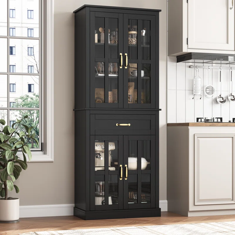 A black 71\“ tall kitchen pantry with glass-paneled double doors, brass handles, and an upper drawer. It features wooden construction and is adjacent to a kitchen countertop, blending storage and display for kitchen items.