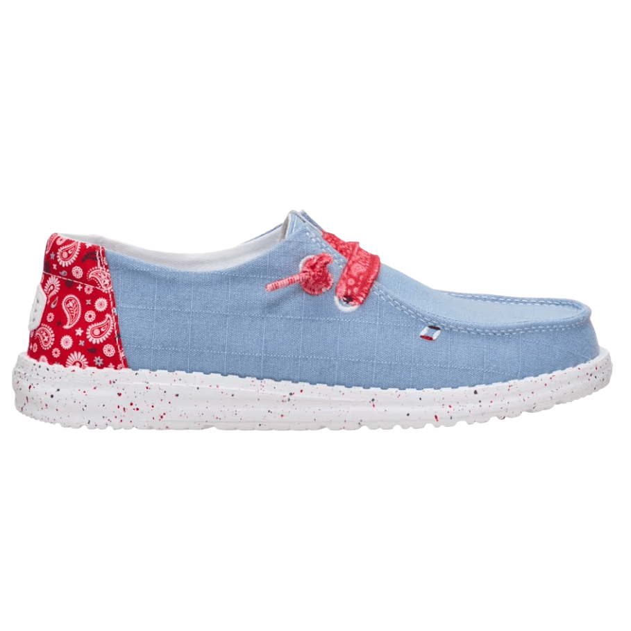 A casual slip-on shoe featuring a light blue upper, red paisley pattern accents, and red speckled white soles.