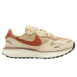 A beige and rust-colored Nike sneaker featuring a prominent Swoosh logo, designed for casual wear with a thick sole and low-top silhouette.