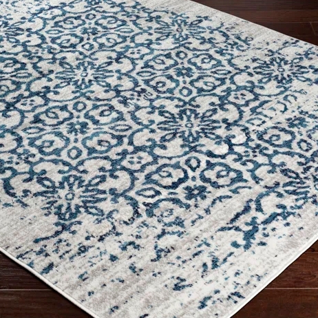A 5' x 7' rug with a floral pattern featuring blue designs on a light background. The rug is stain-resistant and has a distressed look, suitable for enhancing the visual appeal of a room.