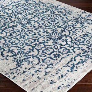 A 5' x 7' rug with a floral pattern featuring blue designs on a light background. The rug is stain-resistant and has a distressed look, suitable for enhancing the visual appeal of a room.