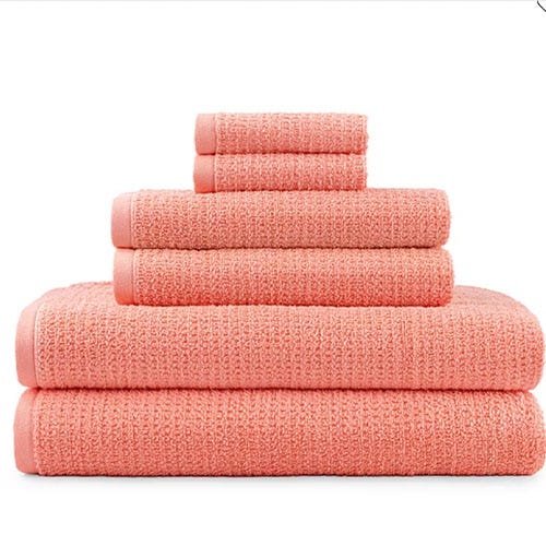 A stack of peach-colored towels in various sizes, neatly arranged from largest to smallest.