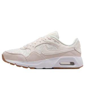 A white and beige athletic shoe with a visible air cushion in the heel and a gum sole, featuring a subtle swoosh logo on the side.