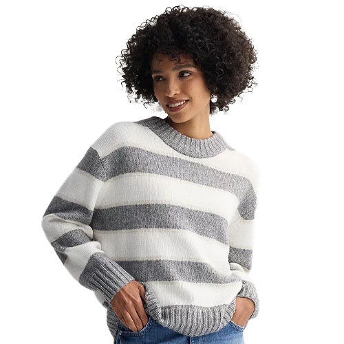 A woman wears a cozy, striped gray and white sweater with long sleeves, paired with jeans.