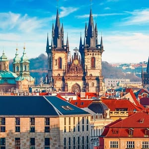 A picturesque view of the Church of Our Lady before Týn, with its Gothic twin spires dominating the skyline, set against a clear blue sky.
