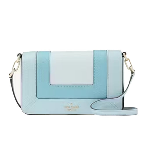 A light blue leather crossbody bag with a flap closure, featuring contrasting panels and gold-tone hardware. It includes an adjustable shoulder strap and a subtle logo on the front.