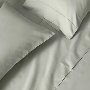 A set of light gray bed sheets, including a flat sheet, fitted sheet, and two pillowcases, neatly arranged on a bed.