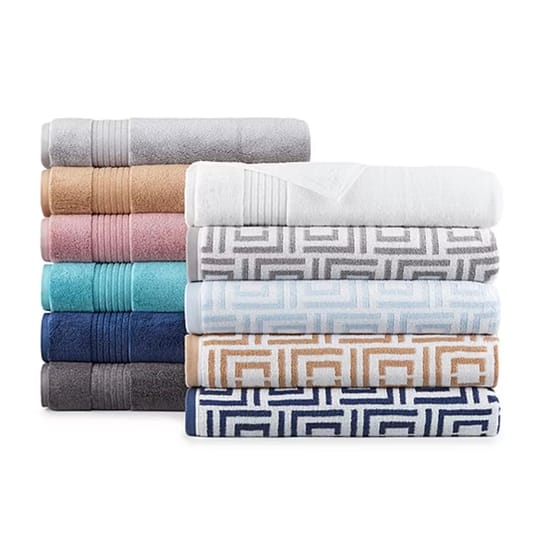 A stack of bath towels in solid colors on the left (gray, beige, pink, turquoise, navy, dark gray) and towels with geometric patterns on the right (white, gray, light blue, beige, navy).