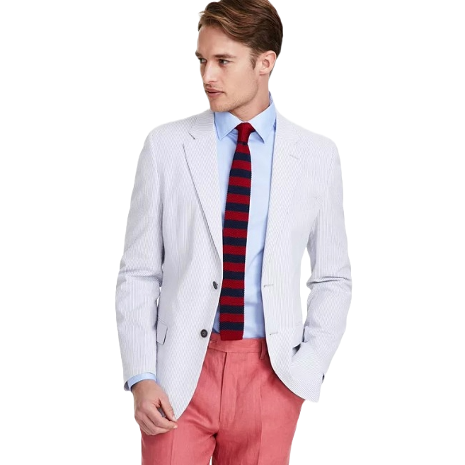 Nautica Modern-Fit Seersucker Sport Coat features a light, textured fabric with a subtle stripe pattern, paired with a light blue shirt and a red and navy striped tie. The look is completed with pink trousers, offering a stylish, modern ensemble.