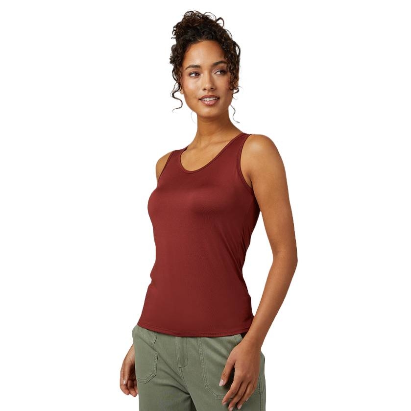 A woman wearing a sleeveless, burgundy tank top paired with green pants.