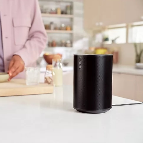 Two cylindrical Sonos Era 100 speakers with a modern design, showcased in a kitchen setting.