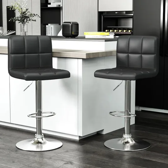 Two modern black bar stools with square-patterned cushioning and adjustable metal bases are positioned at a kitchen counter.