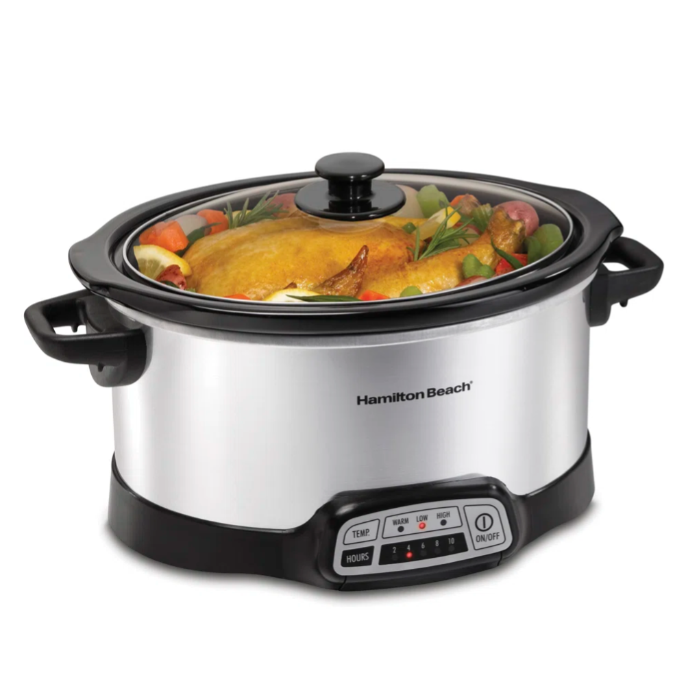 A Hamilton Beach slow cooker with a digital control panel, featuring a stainless steel exterior and a glass lid. It contains a cooked chicken with vegetables.