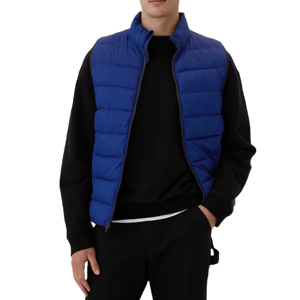 Blue puffer vest with horizontal quilting, worn over a black long-sleeve shirt. The vest features a high collar and zip closure, providing a casual and cozy look.