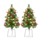 Two small artificial Christmas trees with lights, pine cones, and red berries, set on metal stands.