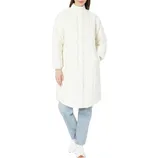 A person is wearing a long, white, quilted coat with a high collar, paired with light blue jeans and white sneakers.