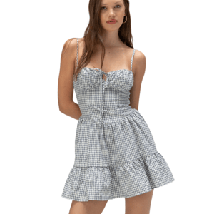 A young woman models a sleeveless gingham checkered dress with spaghetti straps, a button-down front, and a ruffled skirt.