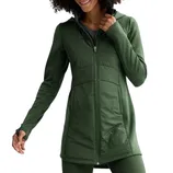 A person is wearing a long, green zip-up jacket with a fitted design, featuring a high collar and long sleeves. The outfit is complemented by matching green leggings.