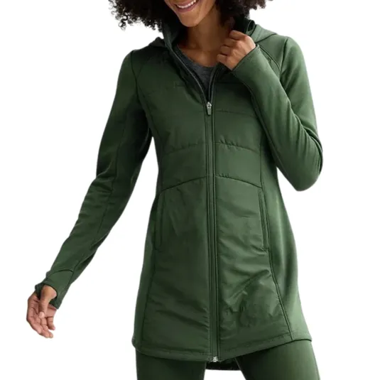 A person is wearing a long, green zip-up jacket with a fitted design, featuring a high collar and long sleeves. The outfit is complemented by matching green leggings.