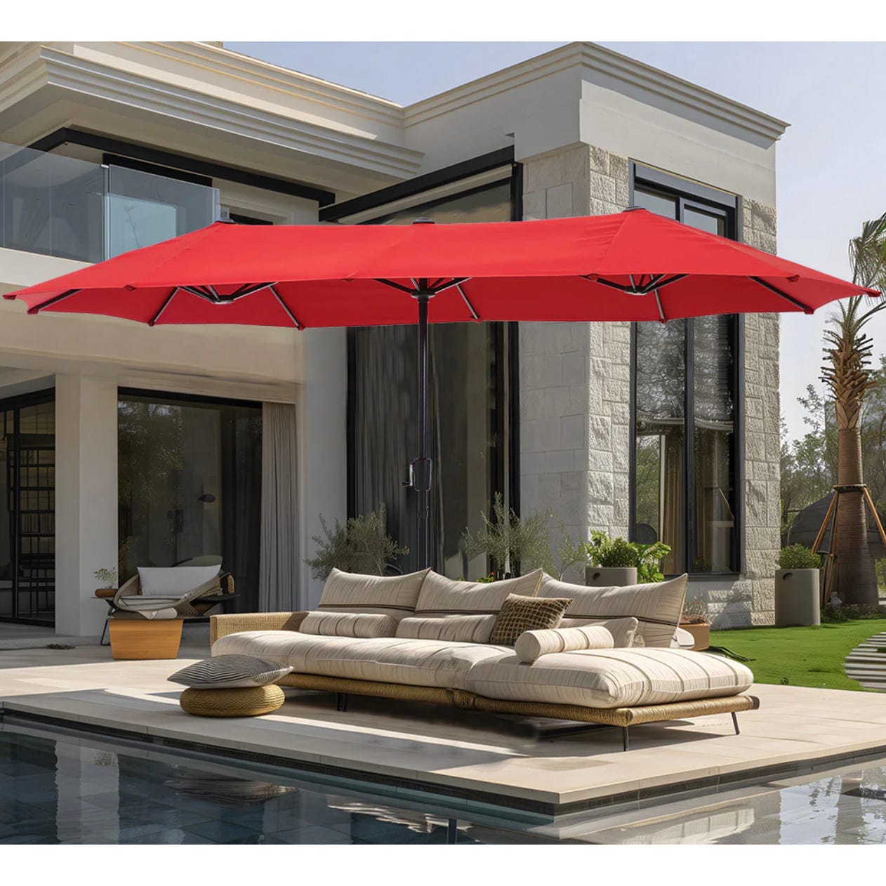 A large red patio umbrella with a sectional outdoor sofa by a swimming pool.