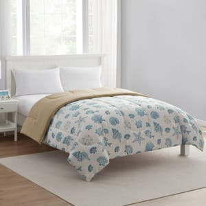 A bedroom features a white bed with a reversible comforter, displaying a beige underside and a blue seashell pattern on top. The room is minimalistic with white pillows, a nightstand, and a window.