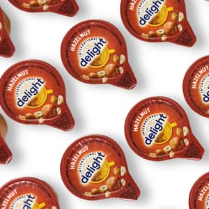 Hazelnut-flavored coffee creamer cups from International Delight, featuring bright packaging with images of hazelnuts and a coffee cup.