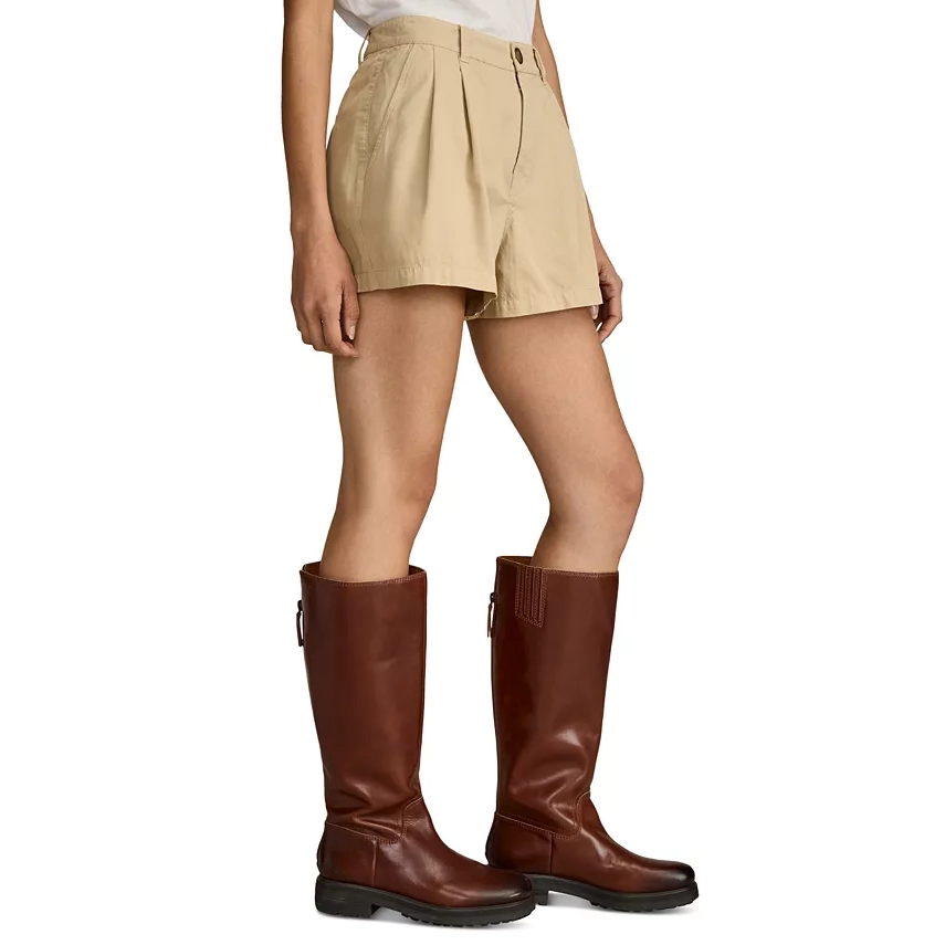 Beige wide-leg chino shorts with a high waist and pleated front are showcased, paired with tall brown leather boots.