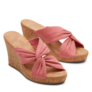 Pink wedge sandals feature cork heels and fabric bows on the front.