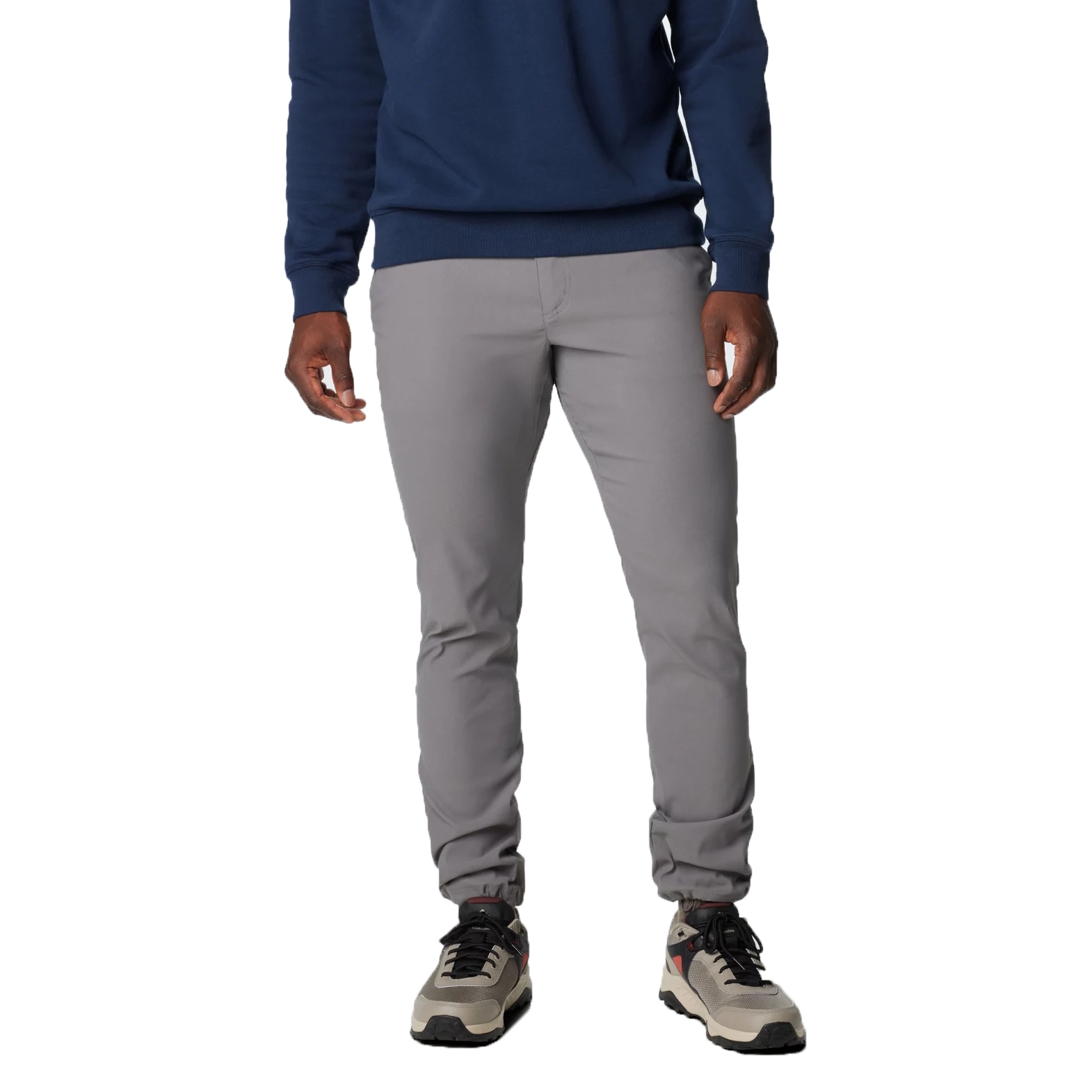 A person is wearing a navy sweatshirt, light gray slim-fit pants, and beige sneakers with black and red details.