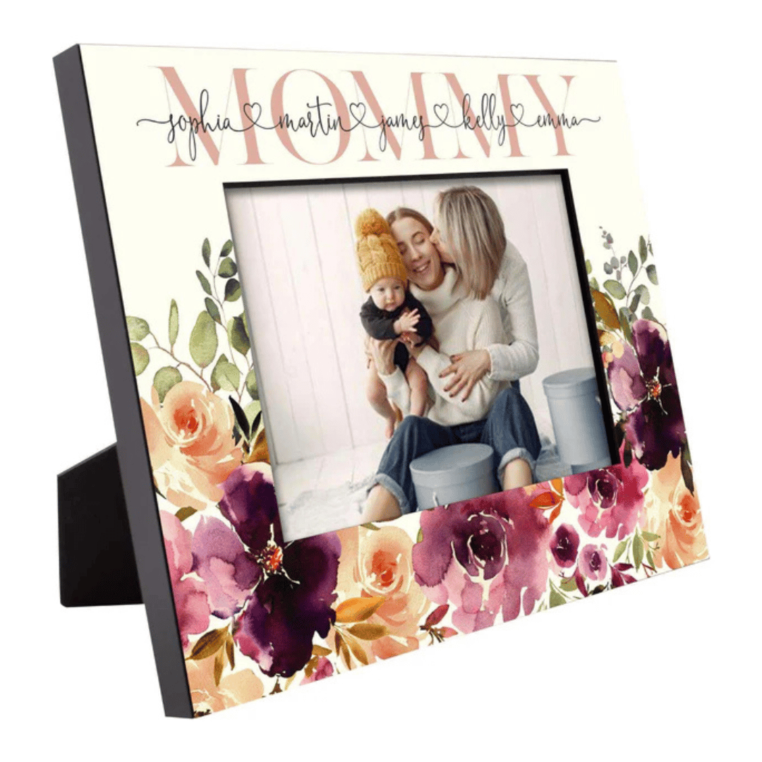 A decorative Mother's Day frame with floral accents, displaying the word \“Mommy\“ and the names \“Sophia, Martin, James, Kelly, Emma\“ at the top. It holds a photo of two adults and a baby, sitting together and smiling.