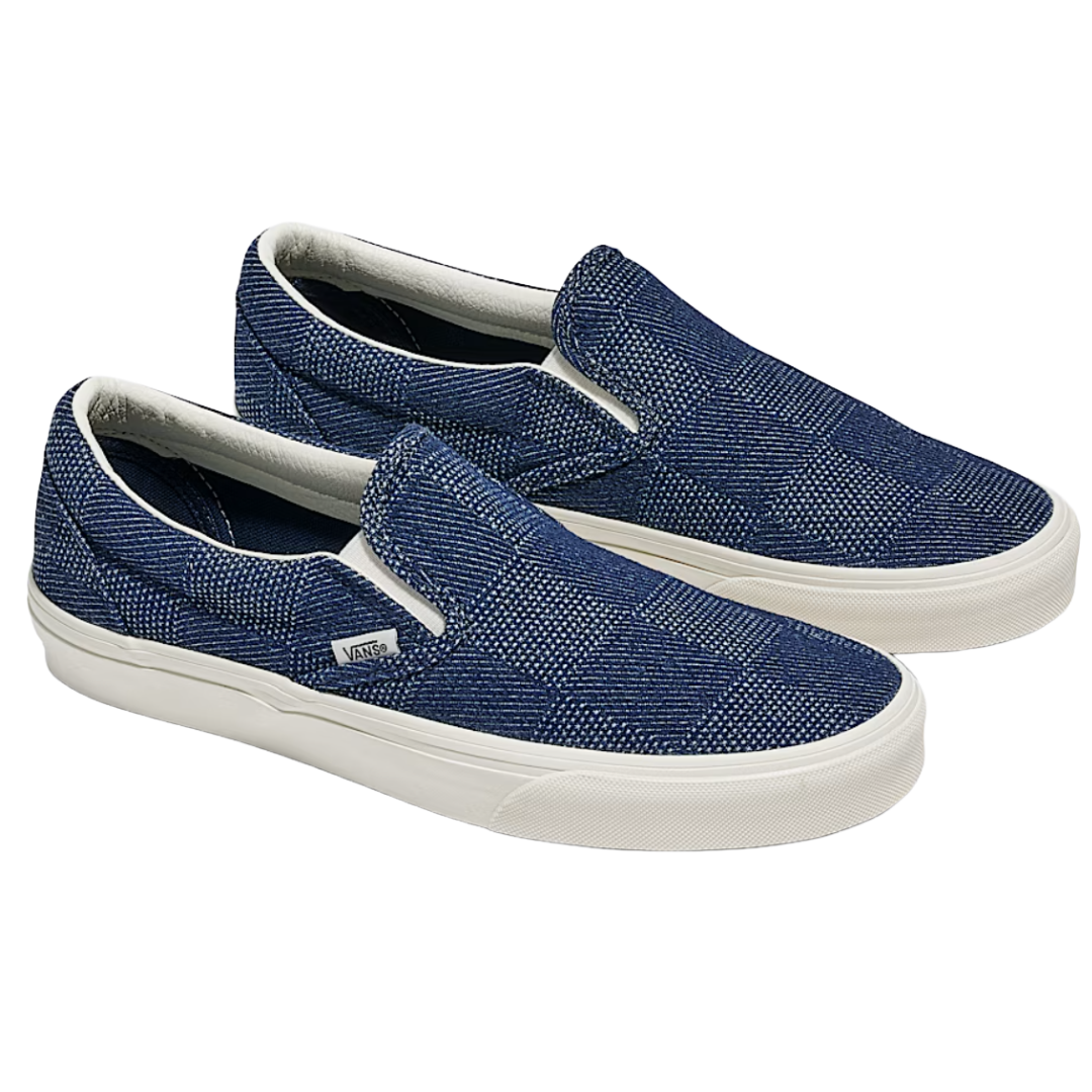 Dark blue slip-on sneakers with a textured checkered pattern and white soles, branded Vans.