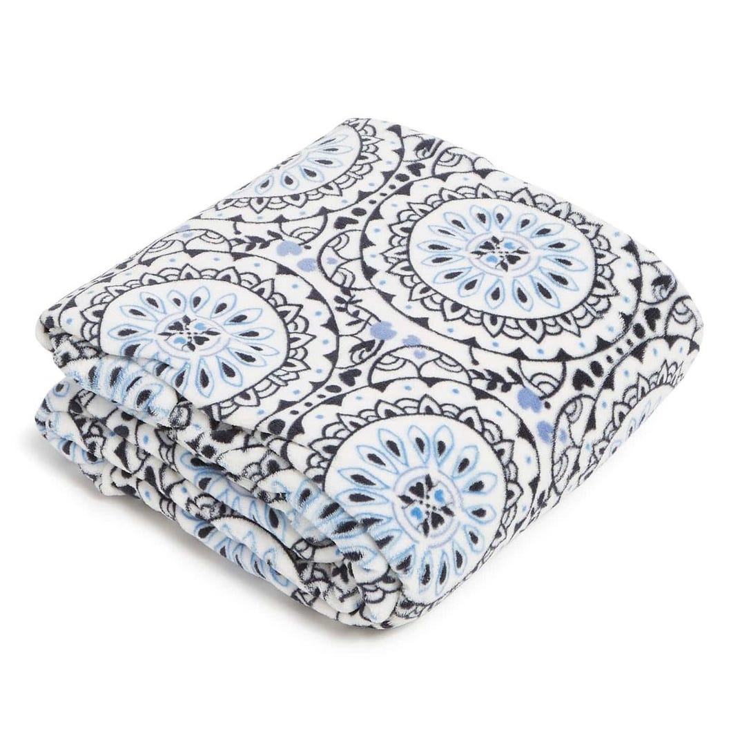 A folded fleece blanket with a blue and black mandala pattern on a white background.