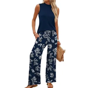 Sleeveless navy top paired with navy wide-leg pants featuring a white floral print, accessorized with a tan clutch and sandals.