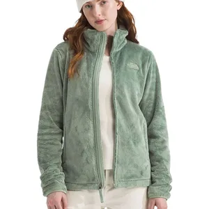 A woman is wearing a light green fleece jacket with a white beanie and shirt, paired with light-colored pants.